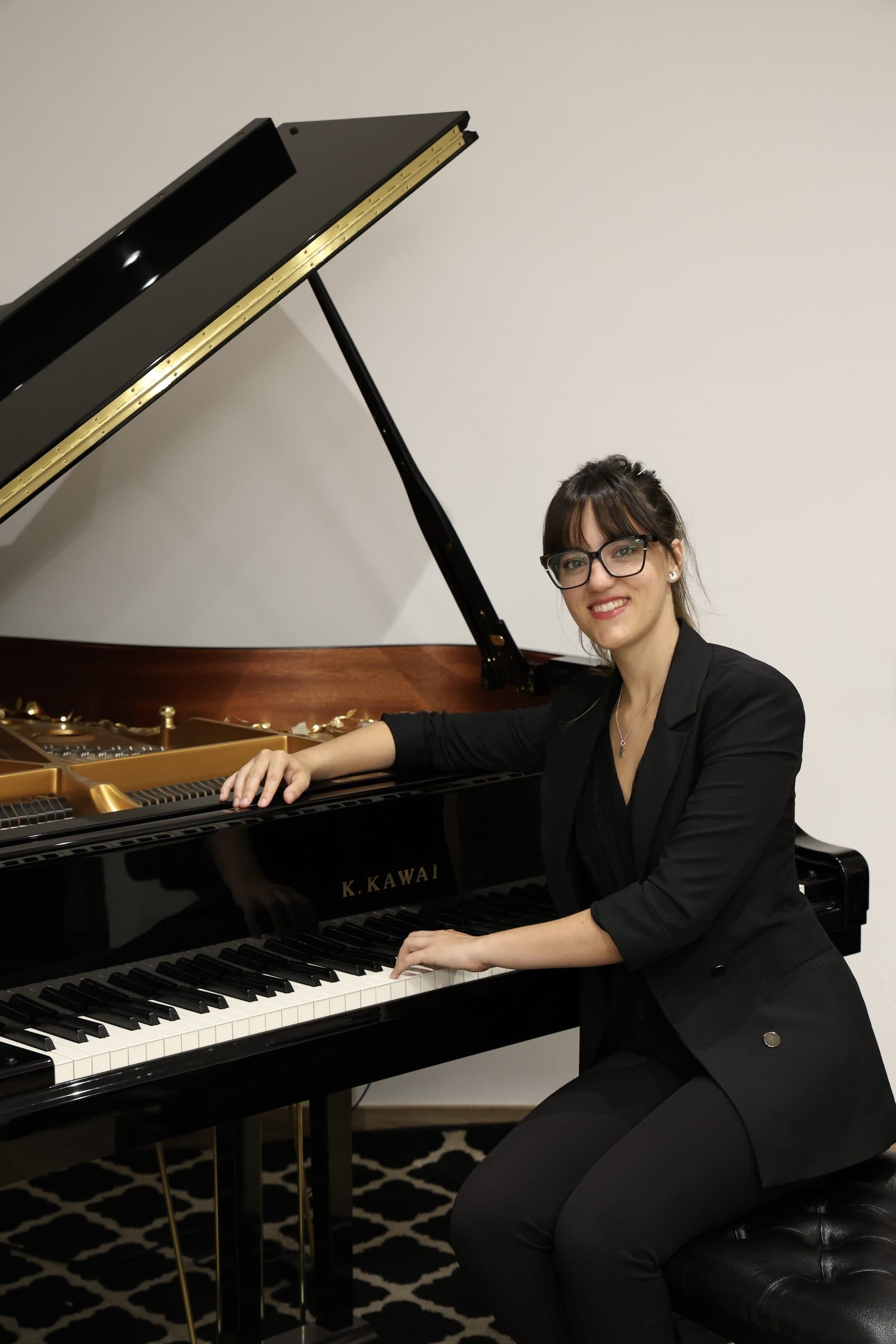 Laura Ortega sentada al piano de cola Kawai GX-2